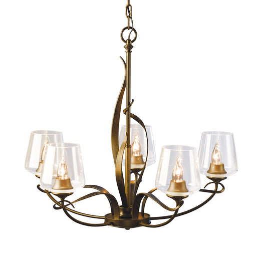 The Flora 5-Arm Chandelier, hand-crafted in Vermont by Hubbardton Forge, features a striking brass finish and elegant clear glass shades.