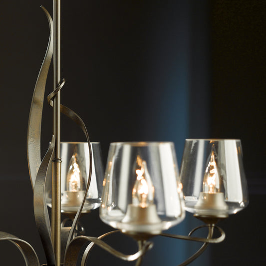 Flora 5-Arm Chandelier by Hubbardton Forge with lit glass bulbs and graceful curved metal design.