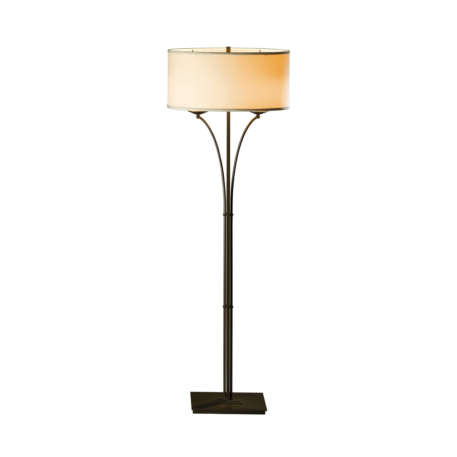 A Hubbardton Forge Formae Contemporary Floor Lamp with a bronze finish, featuring a slender metal post with three curved arms supporting a cream-colored lampshade, hand-crafted and isolated on a white background.