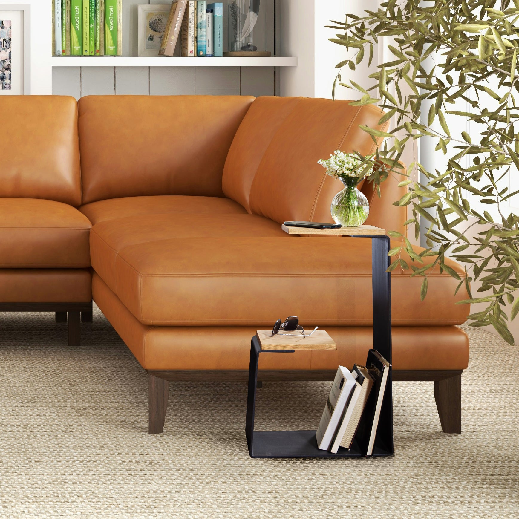 Tan leather sectional with G Table in natural wood from Vermont Woods Studios, featuring a few books and flowers on the tabletop.