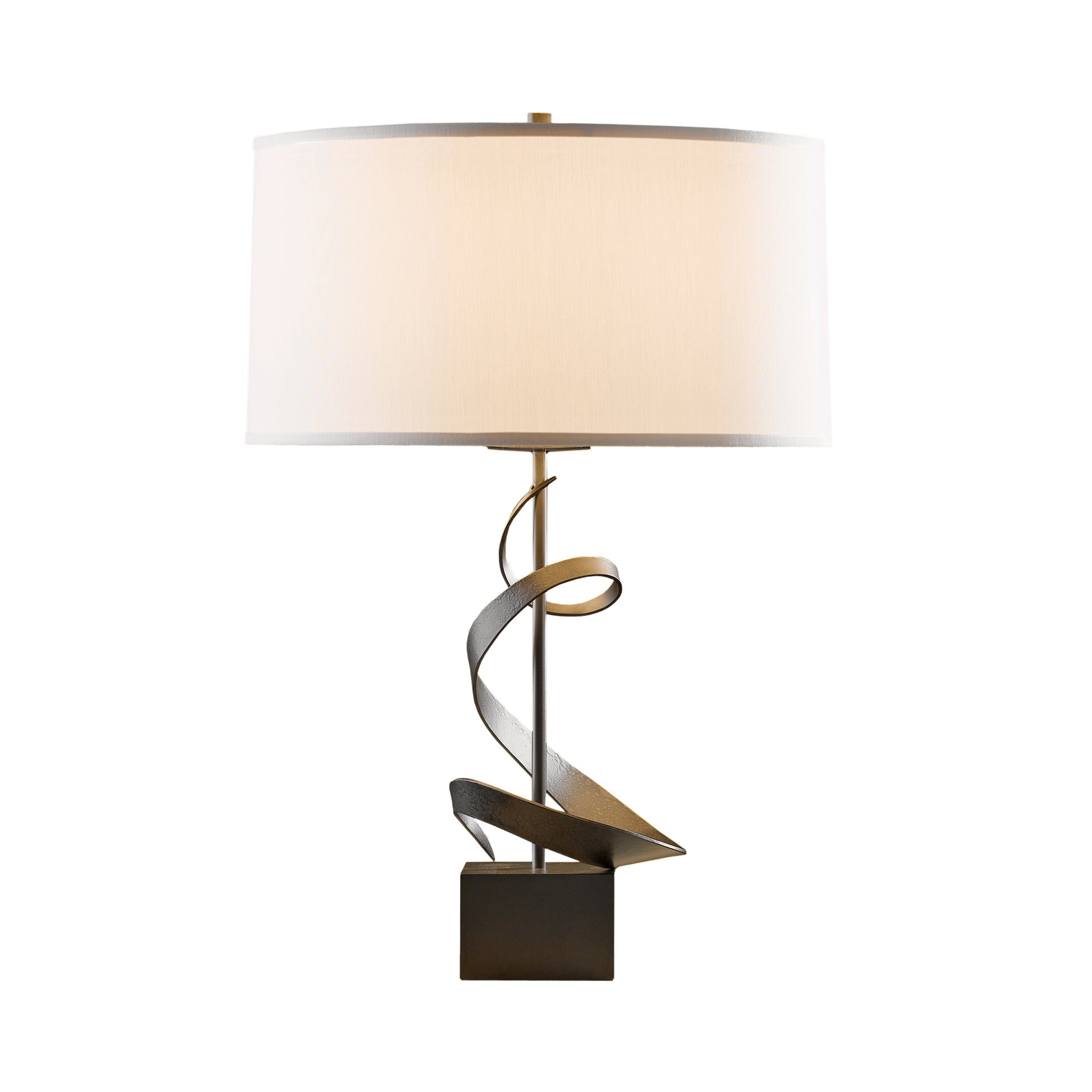 Gallery Spiral Table Lamp by Hubbardton Forge with a white cylindrical shade, twisted metallic base, and square black stand.