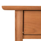 Corner of a Vermont Furniture Designs Heartwood Shaker 1-Drawer Open Shelf Nightstand showing partial view of tabletop and leg with visible wood grain, isolated on a white background.
