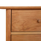 Close-up of a Vermont Furniture Designs Heartwood Shaker 4-Drawer Dresser drawer with a round knob, displaying natural wood grain patterns, against a white background.