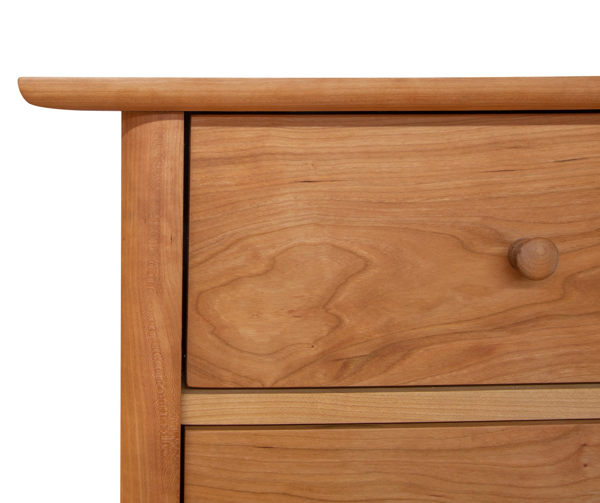 Close-up of a Vermont Furniture Designs Heartwood Shaker 4-Drawer Dresser drawer with a round knob, displaying natural wood grain patterns, against a white background.