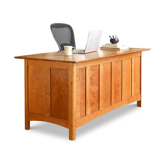A Heartwood Shaker Executive Desk by Vermont Furniture Designs with a laptop, a coffee mug, and some office supplies on its surface, positioned against a white background.