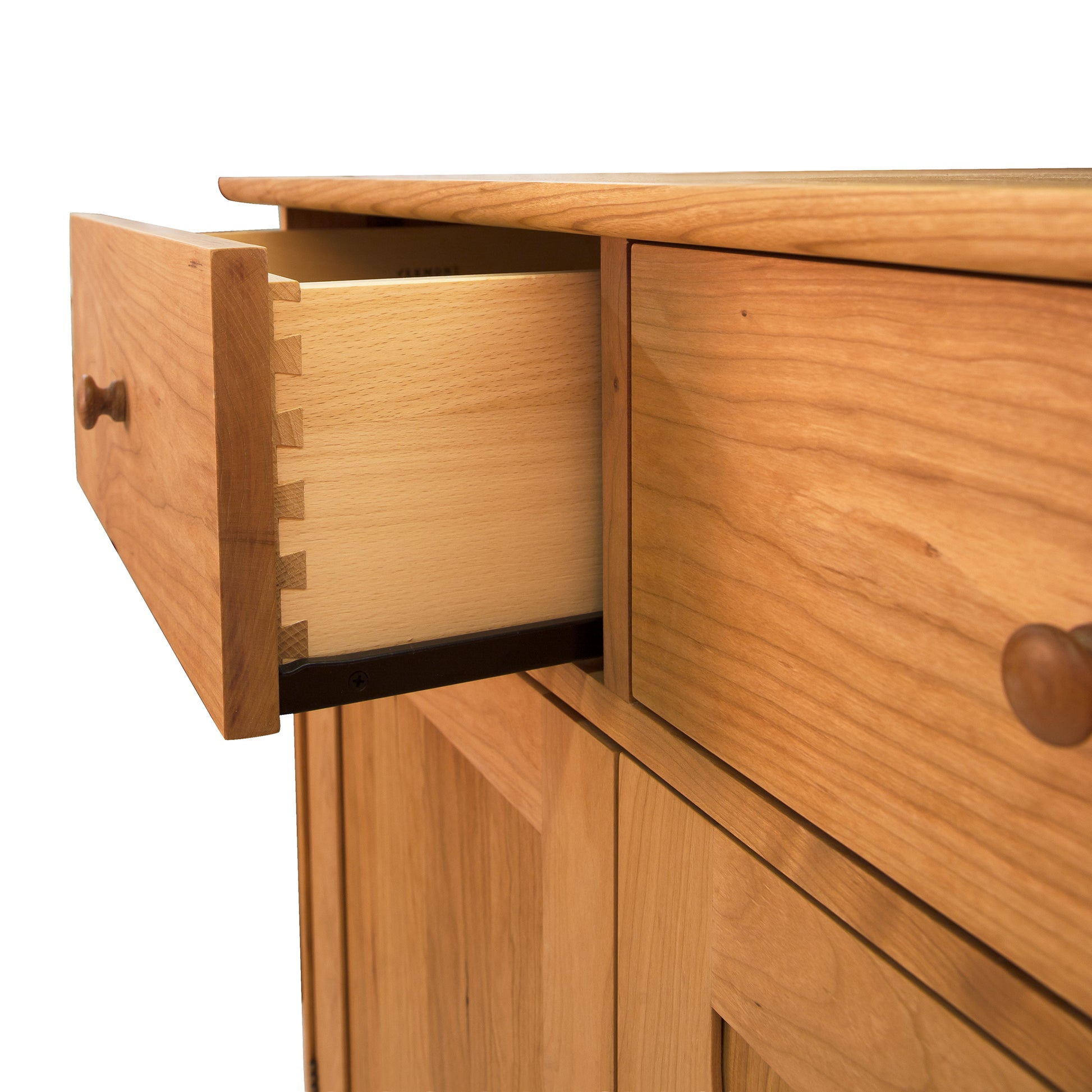 A Vermont Furniture Designs Heartwood Shaker Long Sideboard drawer partially opened, revealing dovetail joints, with the rest of the wooden desk and another drawer visible.