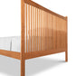 A Heartwood Shaker Low Footboard Bed by Vermont Furniture Designs with vertical slats, showcasing a simple and traditional Arts and Crafts styling, isolated on a white background with bedding partially visible.