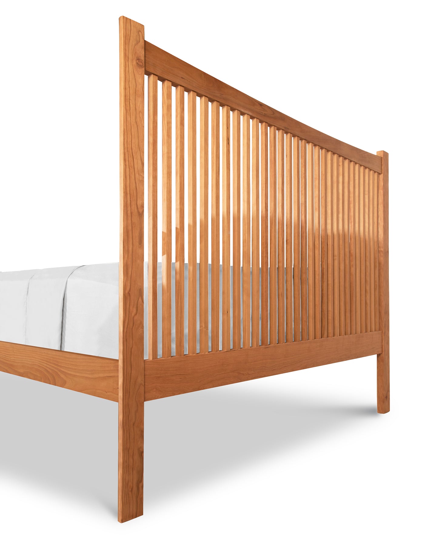 A Heartwood Shaker Low Footboard Bed by Vermont Furniture Designs with vertical slats, showcasing a simple and traditional Arts and Crafts styling, isolated on a white background with bedding partially visible.