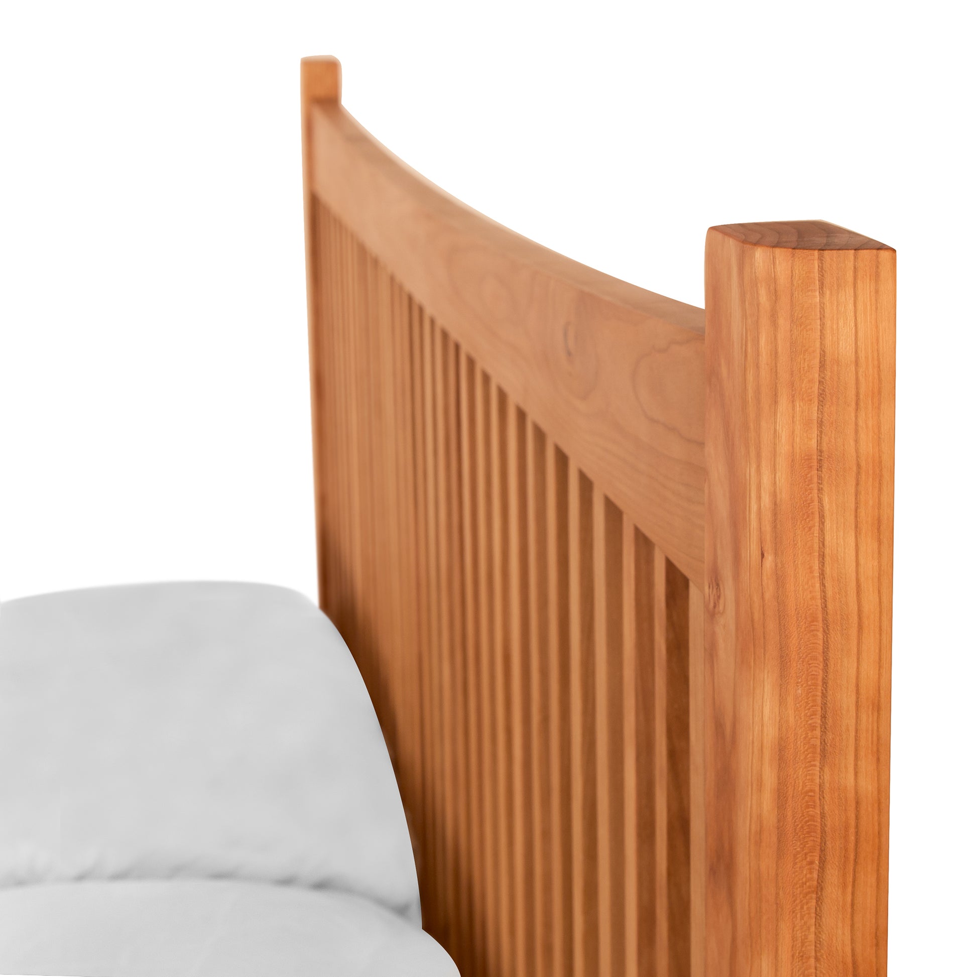 A Heartwood Shaker Low Footboard Bed with vertical slats, featuring a curved top and rich, warm finish in the Arts and Crafts styling. The headboard is attached to a partly visible white mattress. White background.