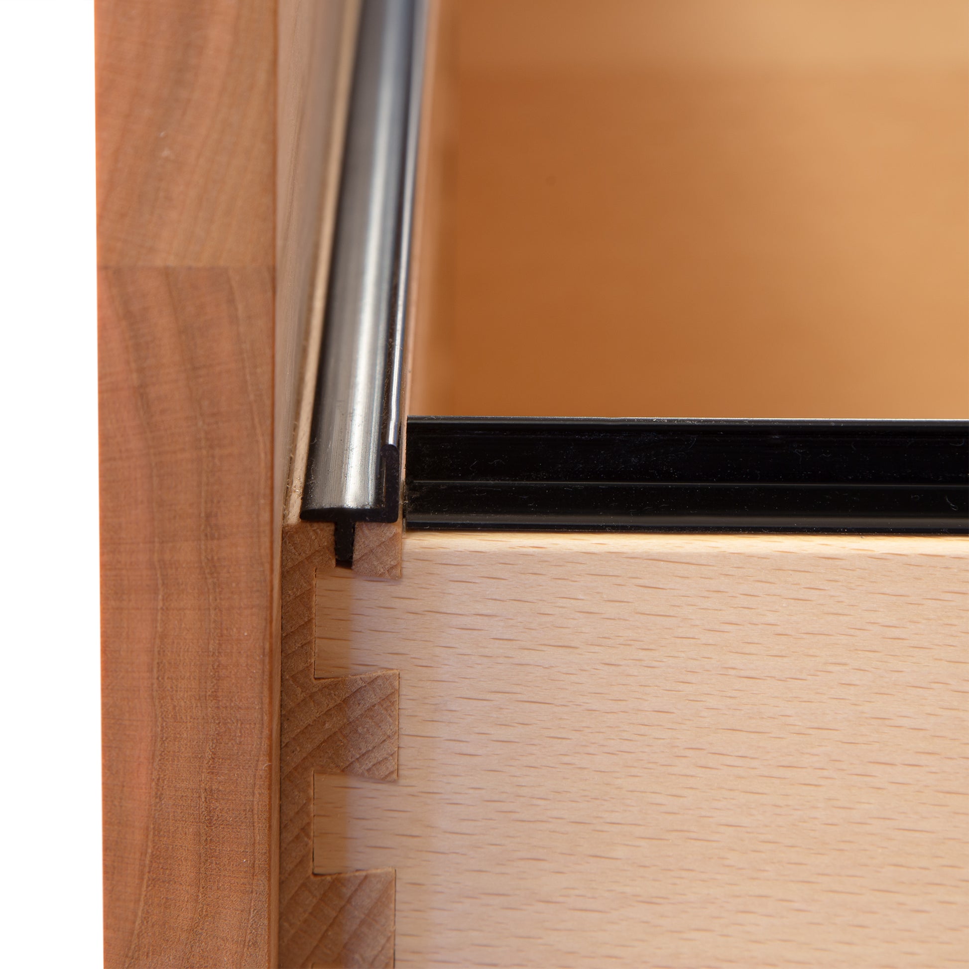 Close-up of a wooden drawer with dovetail joints, featuring a metal drawer slide and partial view of the Vermont Furniture Designs Heartwood Shaker Vertical File Cabinet's interior.