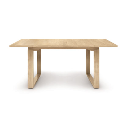 A simple solid oak Iso Extension dining table by Copeland Furniture, with a rectangular top and four legs, isolated on a white background.
