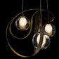A handcrafted Hubbardton Forge Karma Pendant with three glass balls hanging from it.