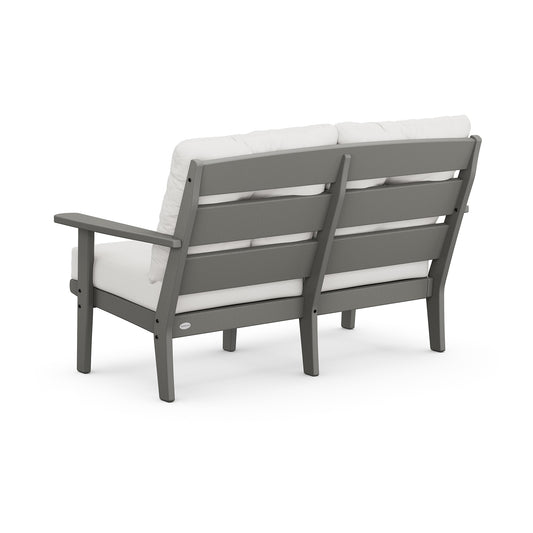 Gray POLYWOOD Lakeside Deep Seating Loveseat with white cushions, showcasing a slatted design and solid armrests.