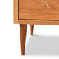Close-up view of the Vermont Furniture Designs Larssen 6-Drawer Dresser with a circular knob, showcasing the grain pattern of the solid wood construction and one of its angled legs against a white background.