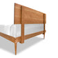 Vermont Furniture Designs Larssen Bed, a wooden platform bed frame with a mid-century modern design, showcasing a high headboard and partially dressed with white bedding, isolated on a white background.