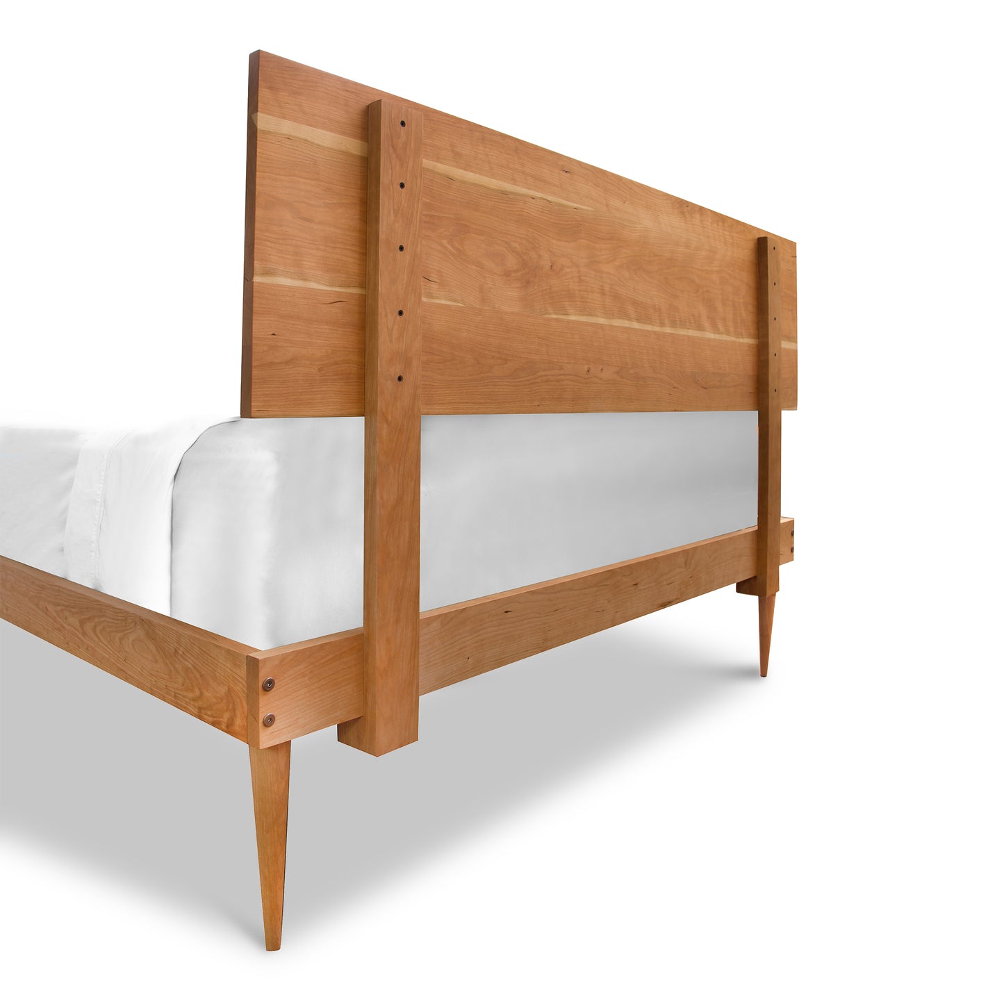 Vermont Furniture Designs Larssen Bed, a wooden platform bed frame with a mid-century modern design, showcasing a high headboard and partially dressed with white bedding, isolated on a white background.