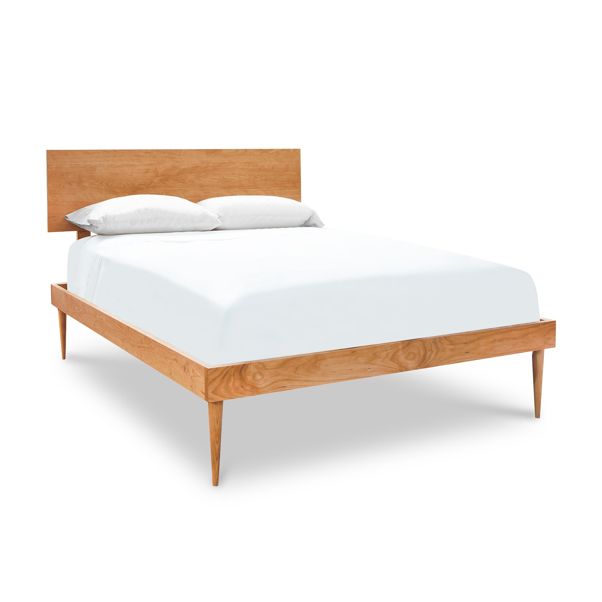 A Vermont Furniture Designs Larssen bed frame in natural cherry wood with a headboard, fitted with white bedding and two pillows, isolated on a white background.