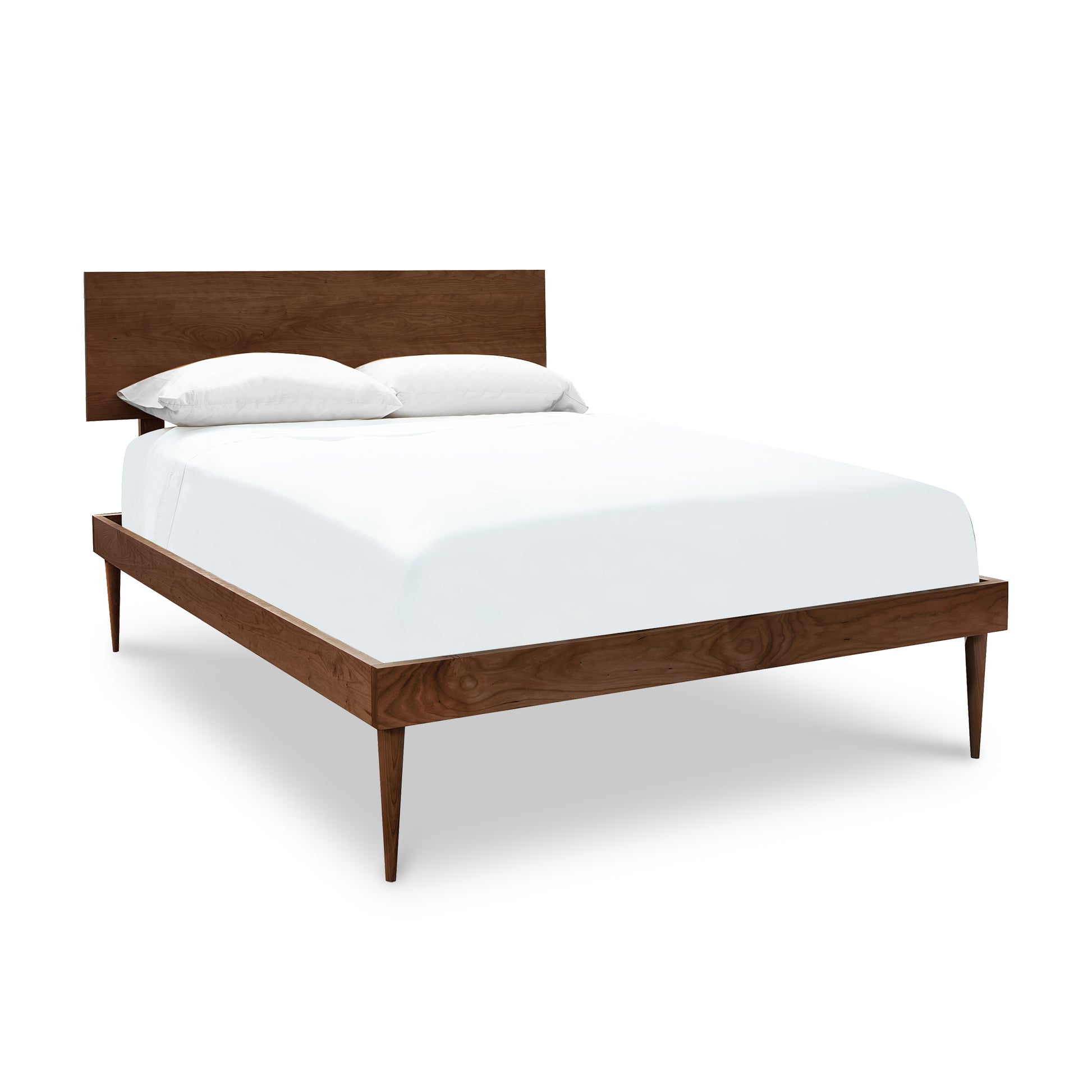 A Larssen Bed platform bed frame made of natural cherry wood with a Vermont Furniture Designs white mattress and pillows isolated on a white background.