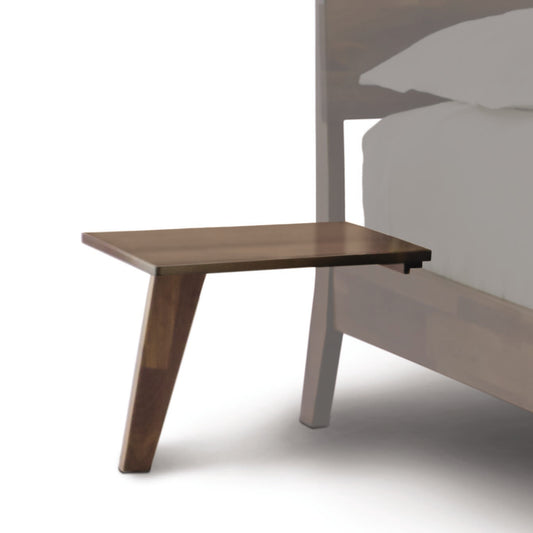 A Linn Walnut Shelf Nightstand by Copeland Furniture on a bed.