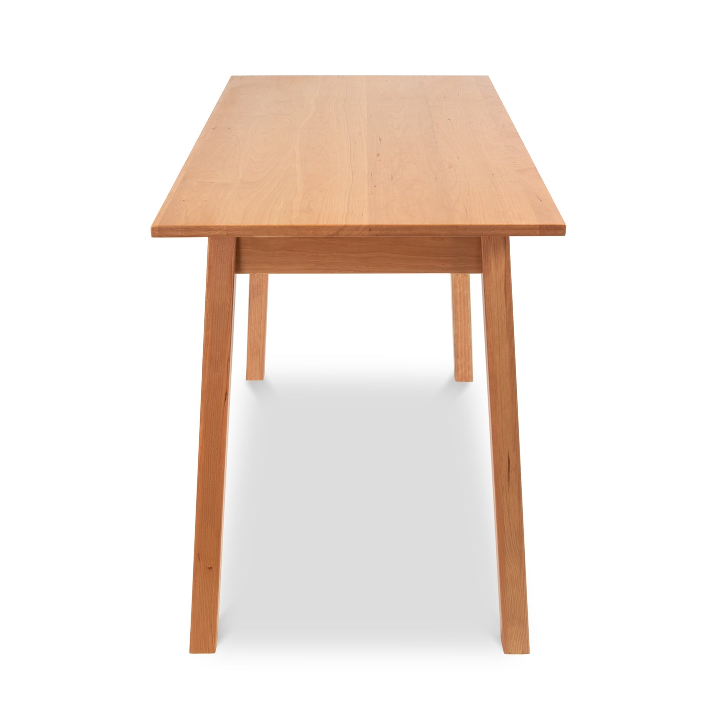 A Manchester Writing Desk made from sustainable solid wood, ideal for modern home offices. This rectangular wooden desk features a natural finish with clean lines and sturdy legs. The minimalist design and smooth surface make it perfect for any workspace. Crafted by Vermont Woods Studios, this American-made furniture piece combines elegance and functionality, seamlessly integrating into your contemporary work environment while promoting sustainable living.