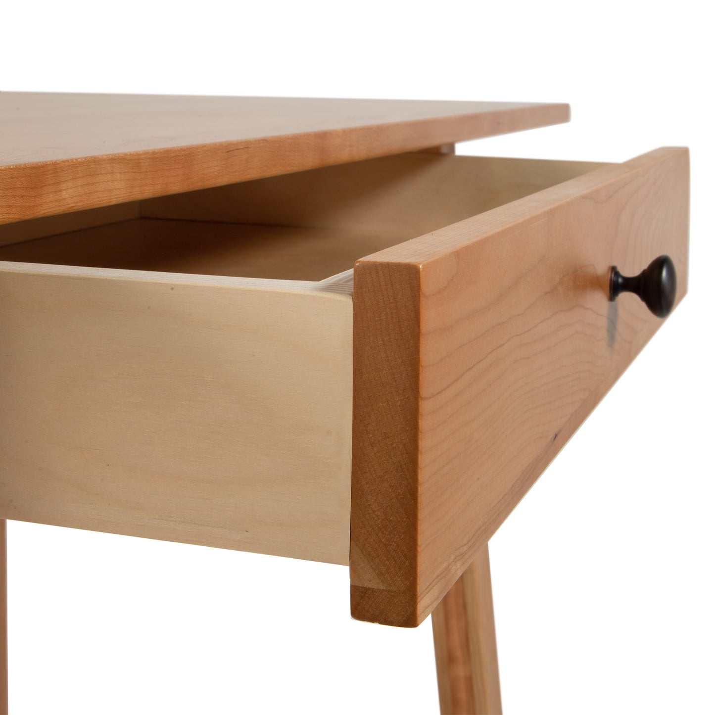 Close-up of a Vermont Woods Studios solid wood Manchester Writing Desk in a modern home office, featuring an open drawer with small black round knob. This sustainable American made desk showcases light-colored wood and sturdy tapered legs. Ideal for those seeking high-quality Vermont furniture, cherry wood furniture, or walnut wood furniture.