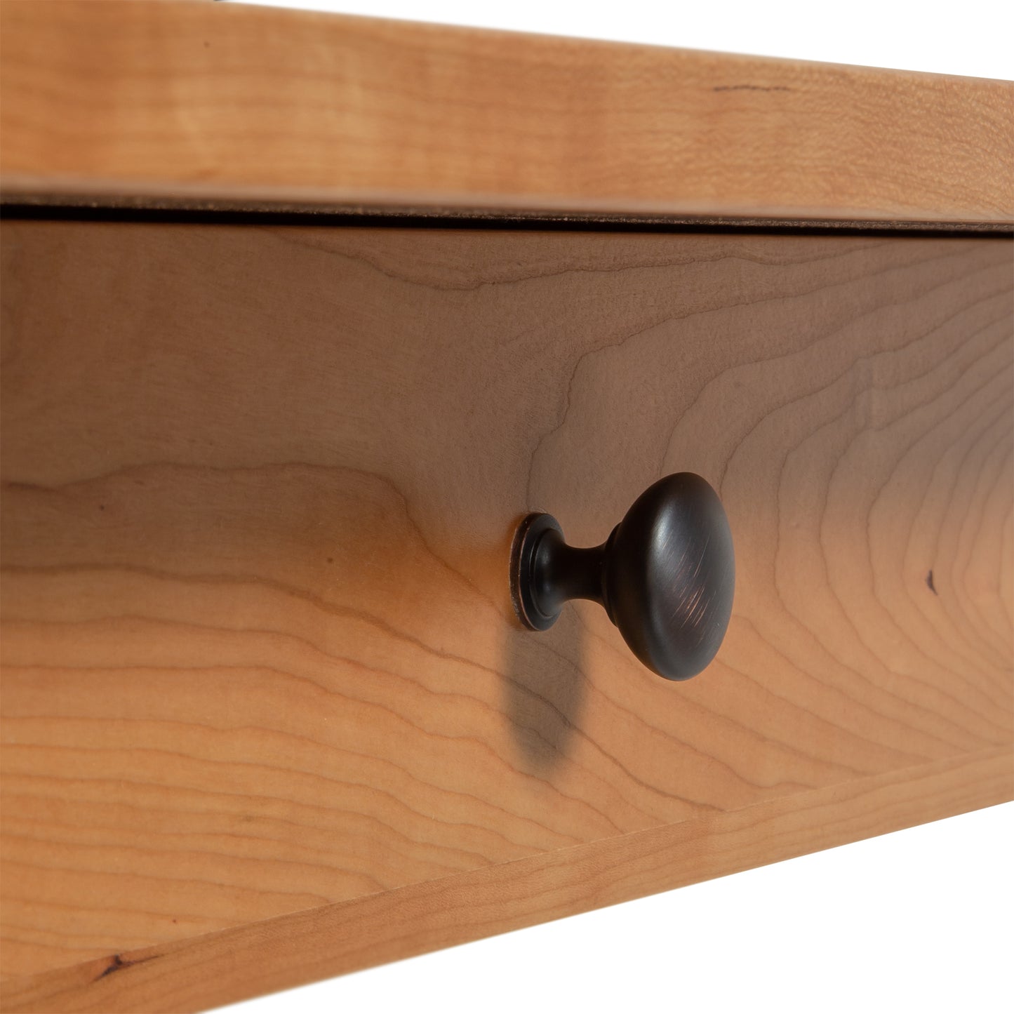 Close-up of wooden drawer with dark round knob on the Manchester Writing Desk from Vermont Woods Studios. Sleek design, smooth cherry wood finish, and visible wood grain patterns. Ideal for a modern home office setup with quality American made furniture.