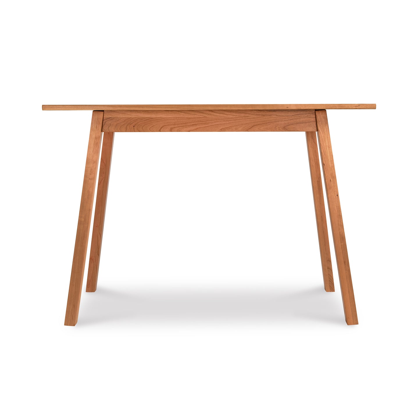 Alt text: Manchester Compact Desk in light brown wood featuring minimalist design from Vermont Woods Studios. Solid wood desk with rectangular top, four angled legs, and clean natural finish, perfect for home office or small spaces. American made furniture set against a white background.