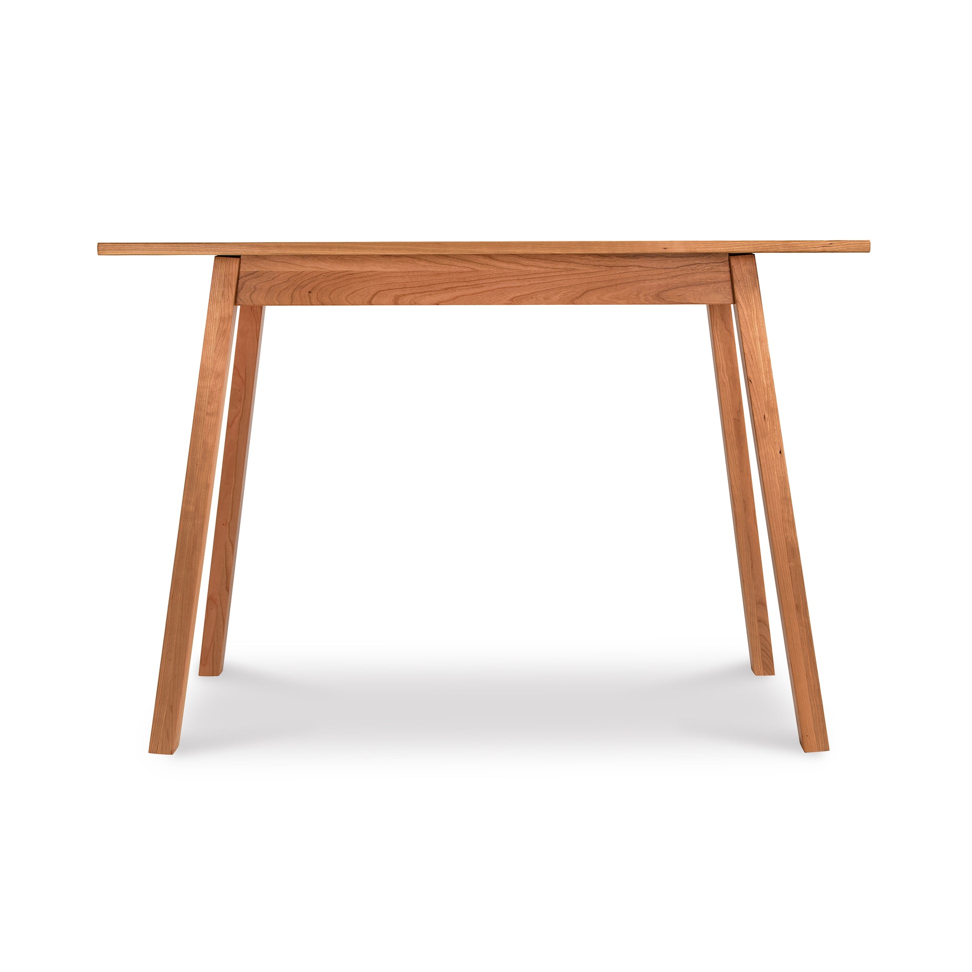 Alt text: Manchester Compact Desk in light brown wood featuring minimalist design from Vermont Woods Studios. Solid wood desk with rectangular top, four angled legs, and clean natural finish, perfect for home office or small spaces. American made furniture set against a white background.