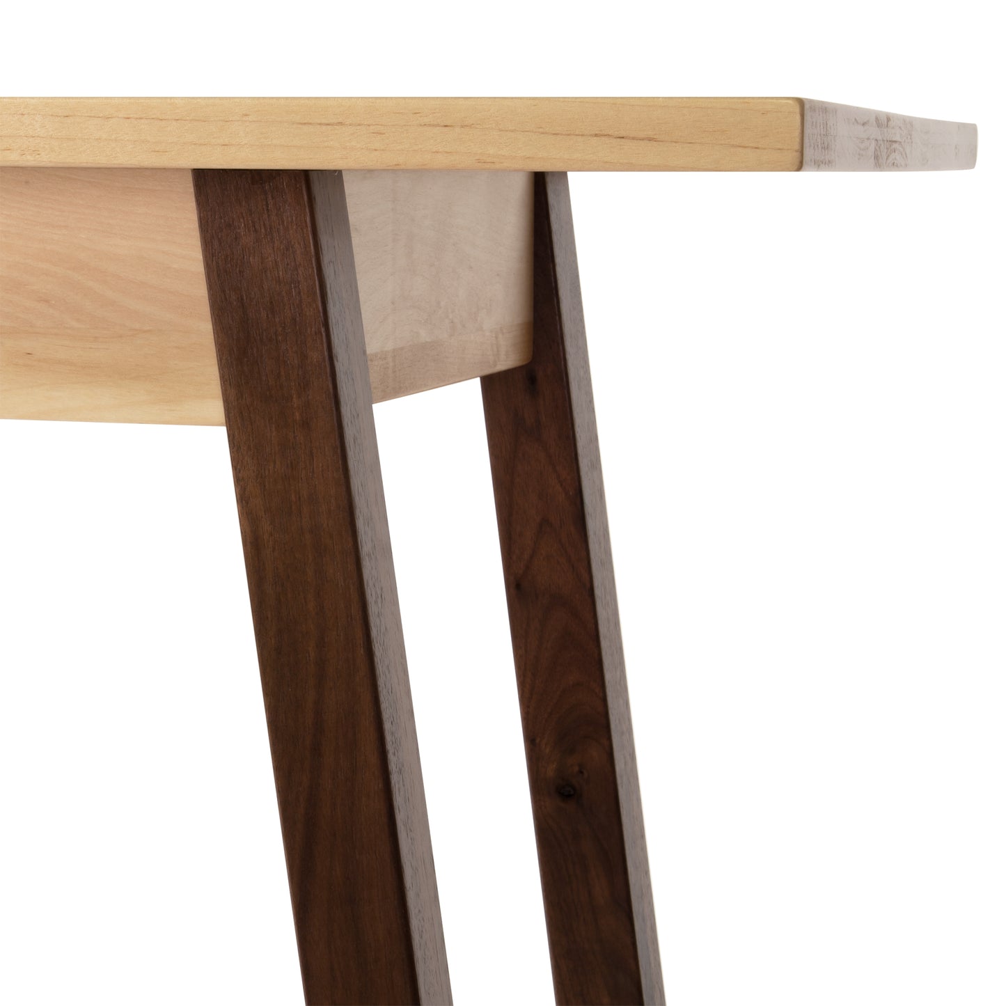 Close-up of the Manchester Two-Tone Compact Desk by Vermont Woods Studios, an American made, handcrafted solid wood desk. Featuring a light brown cherry wood tabletop and darker walnut wood angled legs, this modern 21st century desk adds elegance with its smooth, polished finish. Perfect for home offices or small spaces seeking high quality furniture made in Vermont.