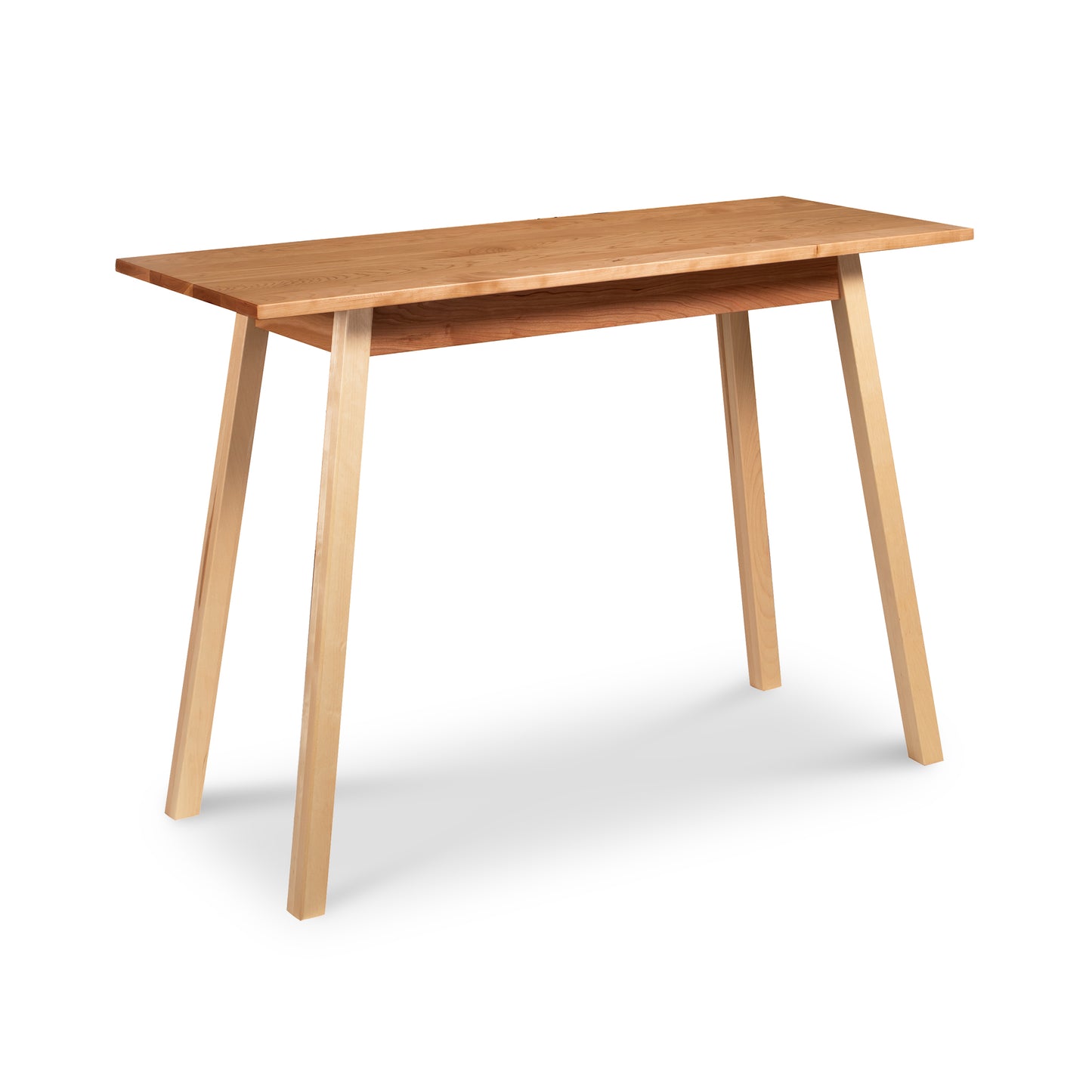 A handcrafted solid wood desk with a minimalist design, this Manchester Two-Tone Compact Desk by Vermont Woods Studios features a rectangular top surface and four angled legs. Its natural wood finish highlights the grain and texture of high-quality American made cherry wood or walnut wood, making it perfect for a modern 21st-century home office.
