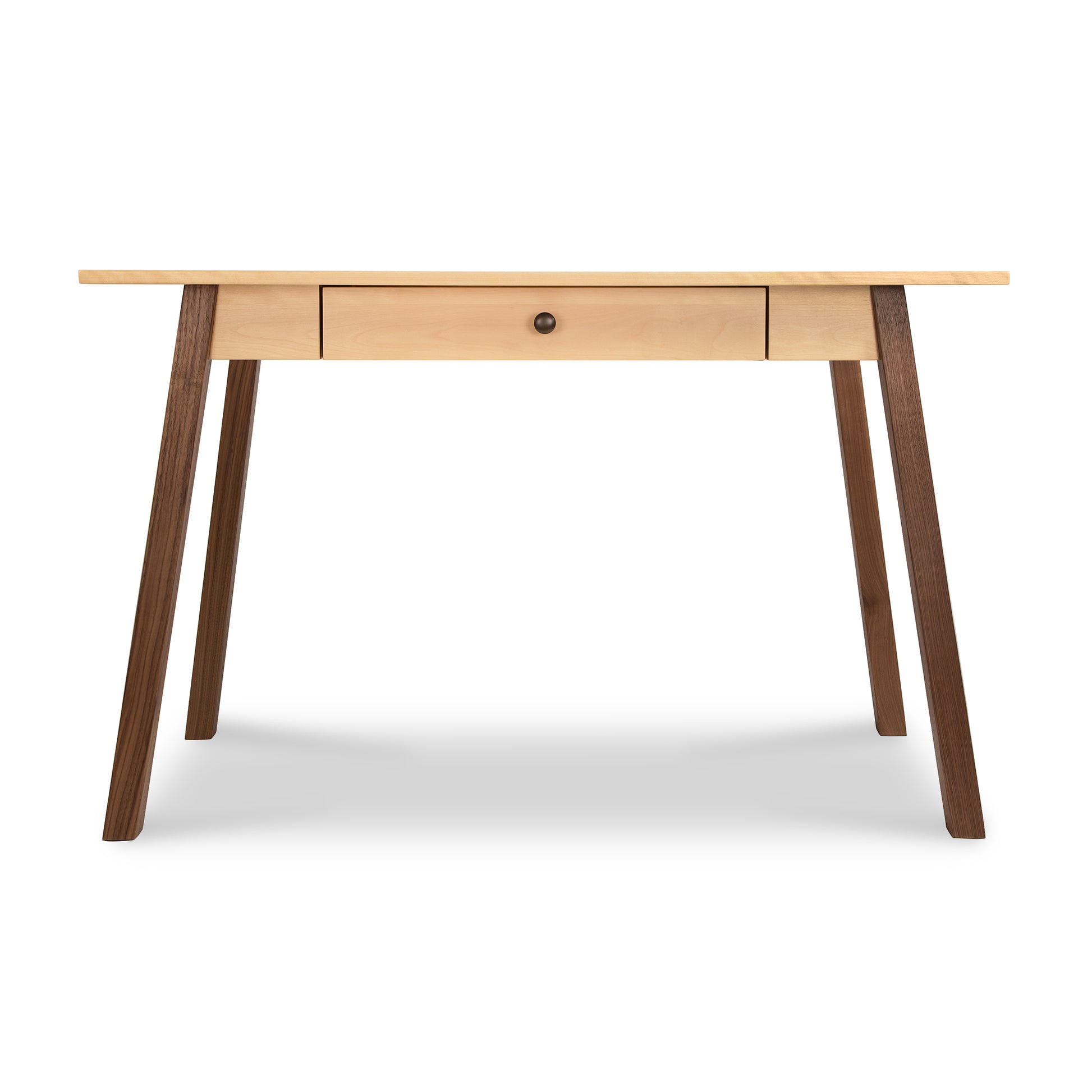 A modern wooden desk named the Vermont Woods Studios Manchester Two-Tone Writing Desk, featuring a single centered drawer, with a light wood tabletop and contrasting darker wood legs made from sustainable solid wood, isolated on a white background.