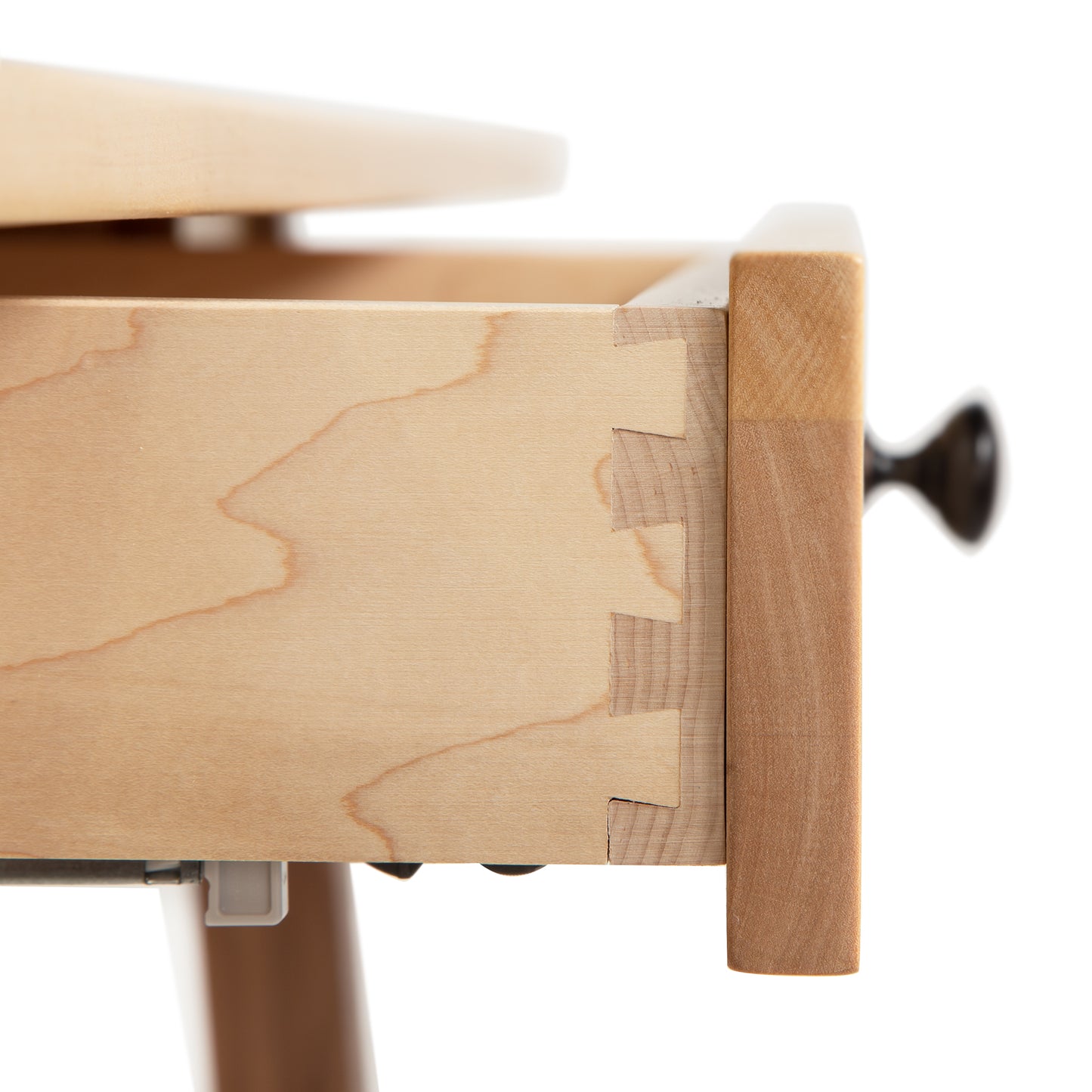 Close-up of a wooden drawer with dovetail joints, part of a Manchester Two-Tone Writing Desk made by Vermont Woods Studios from sustainable solid wood with a smooth finish and a knob.