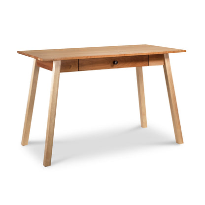 The Vermont Woods Studios Manchester Two-Tone Writing Desk, crafted from sustainable solid wood, features a single centered drawer and tapered legs with a smooth, natural finish. Set against a white background, the desk showcases its clean, simple design.