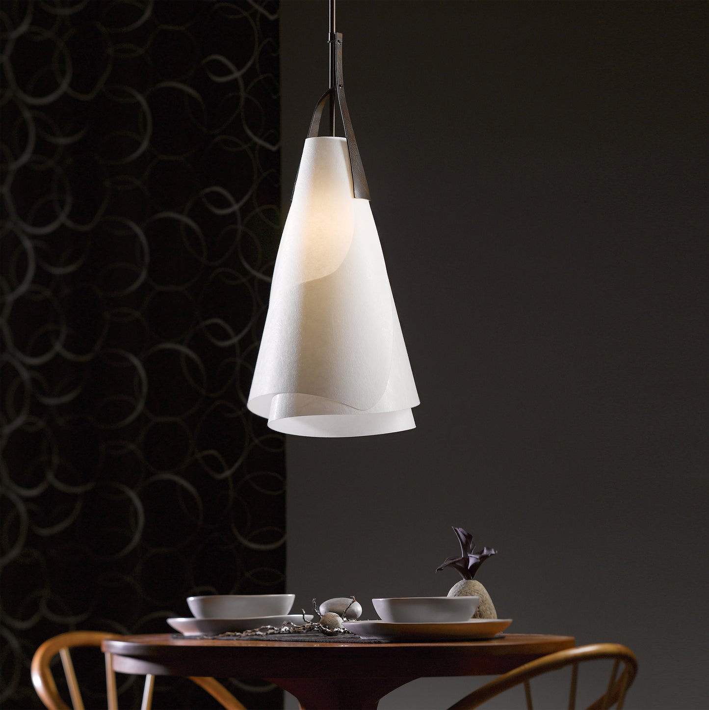 Hubbardton Forge Mobius Tall Pendant illuminating a sleek small table with elegant bowls and teapot.