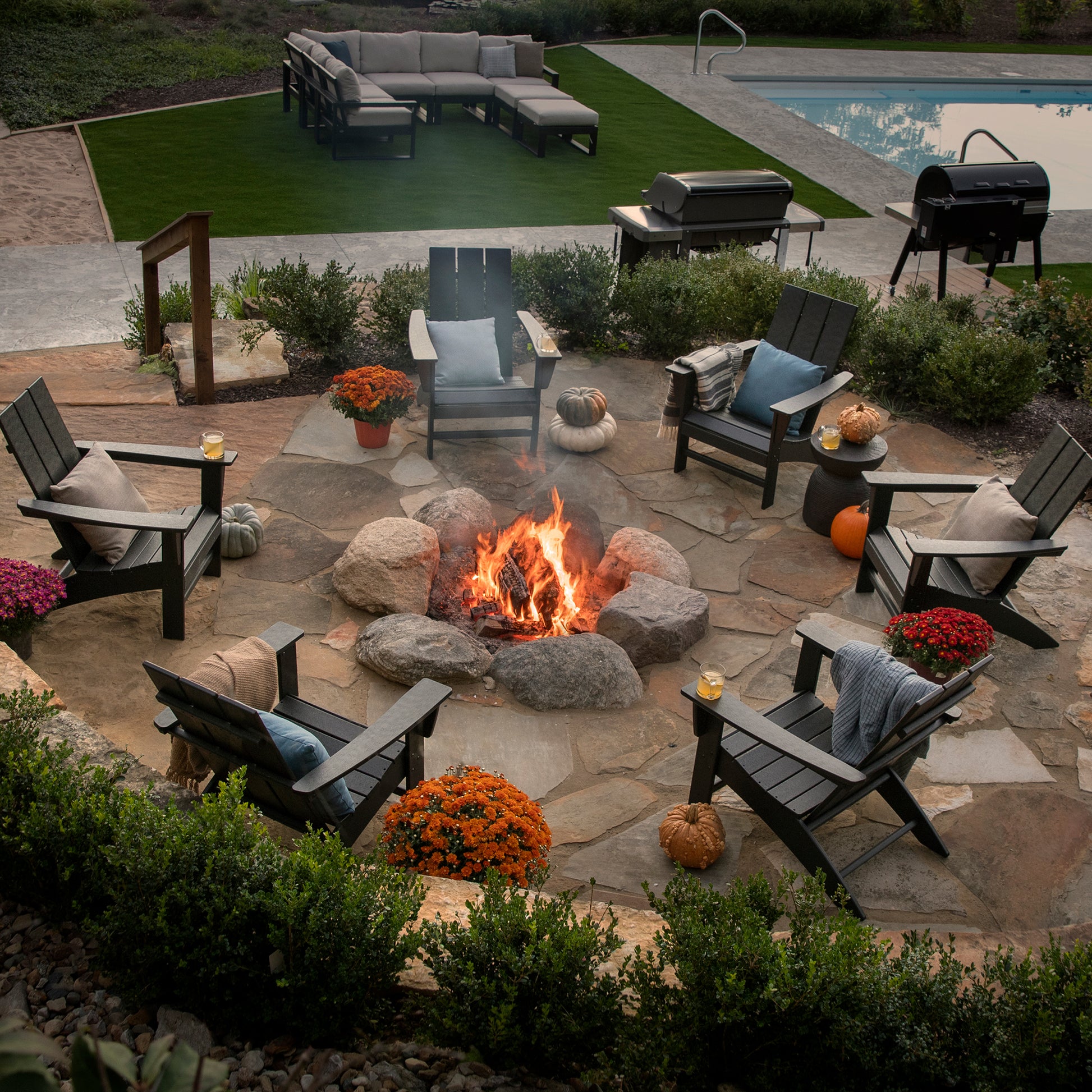 Modern Adirondack chairs by POLYWOOD arranged around a fire pit, showcasing sleek outdoor furniture design.