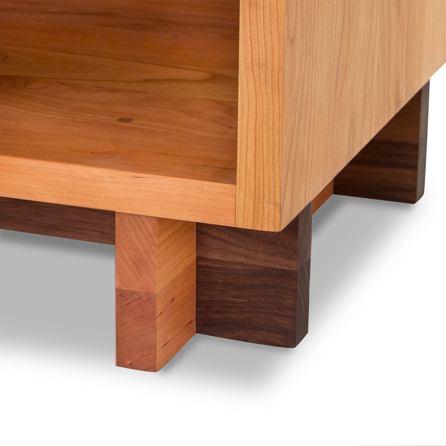 Close-up of a Vermont Furniture Designs Modern American 1-Drawer Enclosed Shelf Nightstand showing the details of its construction, focusing on the joint area where two types of wood meet.