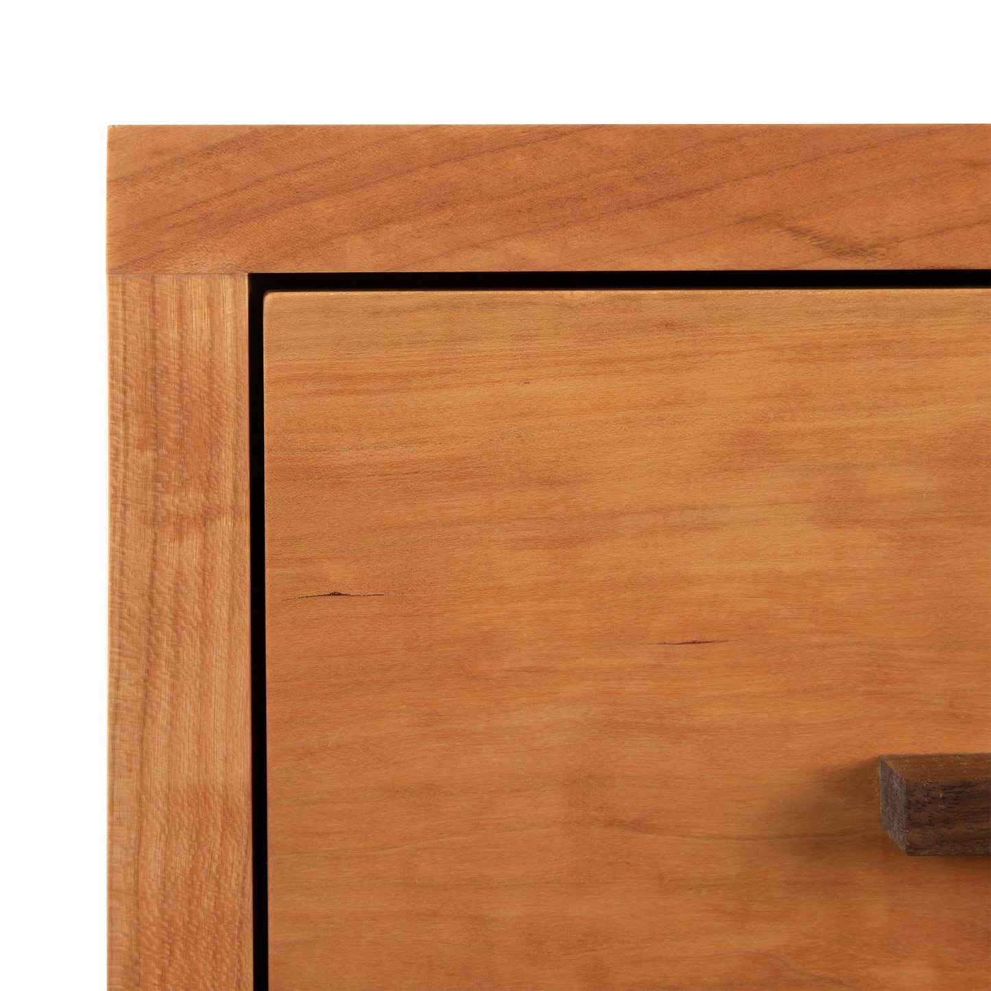 Close-up view of a Vermont Furniture Designs Modern American 1-Drawer Enclosed Shelf Nightstand with a minimalist design, highlighting the grain and texture of the wood and a visible handle on the right side.