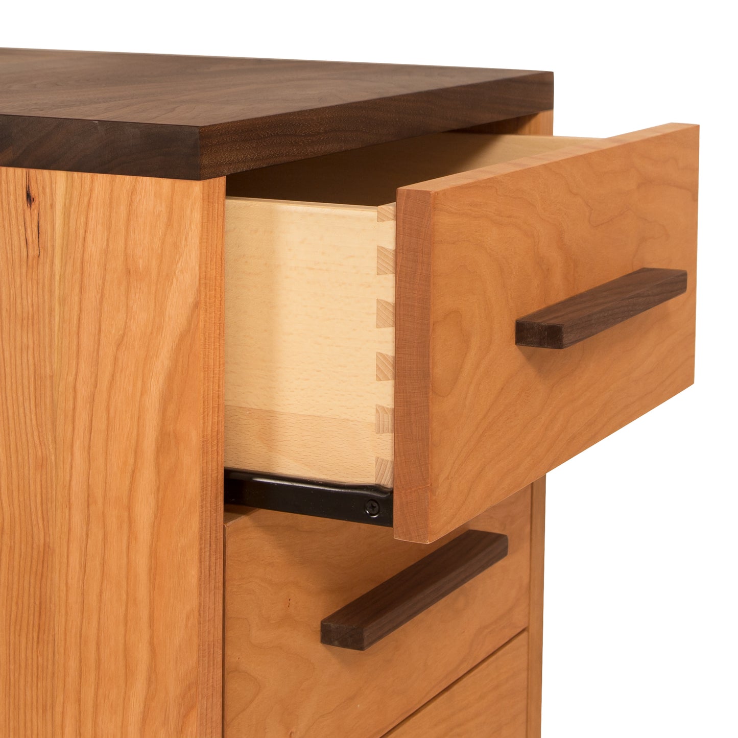 A close-up view of an open drawer in a wooden dresser, showing the dovetail joints and smooth interior, with an eco-friendly oil finish and simple rectangular handles on the Vermont Furniture Designs Modern American 3-Drawer Nightstand.