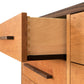 Close-up view of an open drawer in a Vermont Furniture Designs Modern American 8-Drawer Dresser #1, showcasing precise dovetail joints and smooth finish. The surrounding drawers are closed, featuring sleek, rectangular handles.