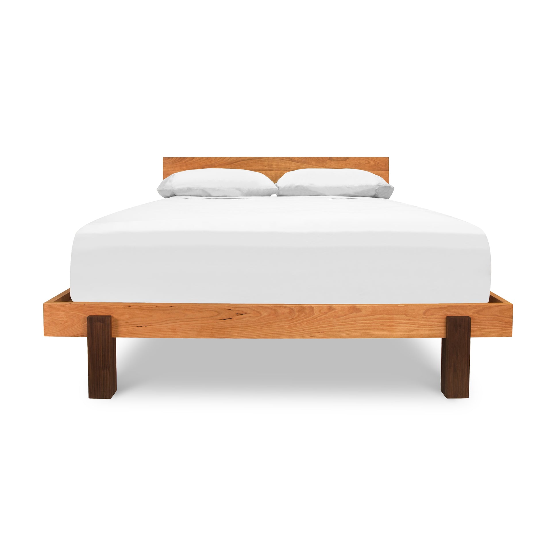 A simplistic Vermont Furniture Designs Modern American Platform Bed made of solid hardwoods, with a white mattress and two pillows, isolated on a white background.