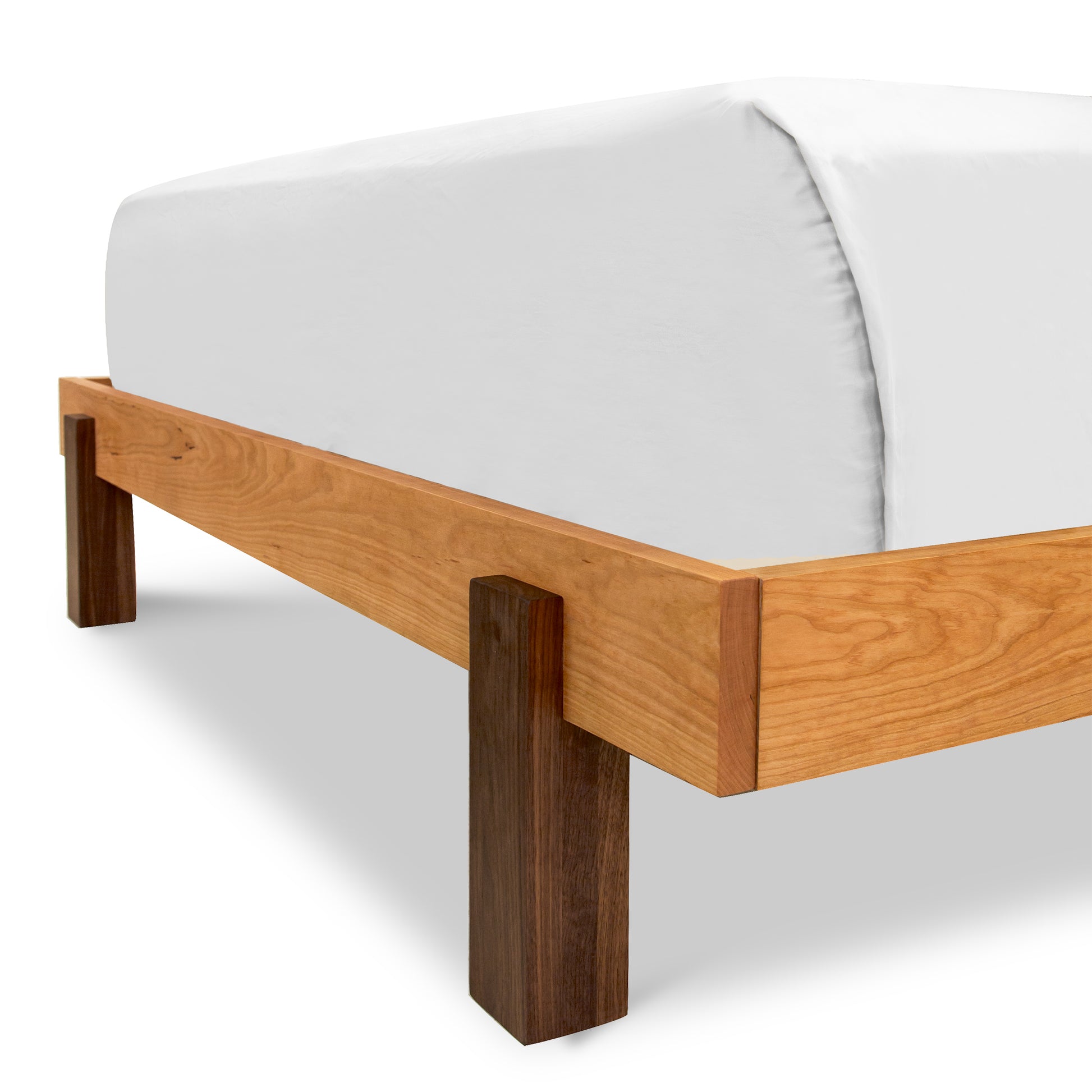 A minimalist wooden Modern American Platform Bed frame from Vermont Furniture Designs, crafted from solid hardwoods, with a corner view showcasing clean lines and a white mattress without bedding as part of our Modern American Platform Bedroom Furniture collection.