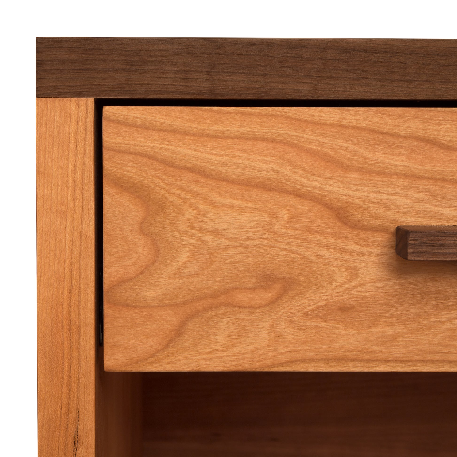 Close-up image of a Vermont Furniture Designs Modern American 1-Drawer Enclosed Shelf Wide Nightstand drawer slightly open, showing the detailed wood grain and texture on the drawer face with a simple horizontal pull handle. The outer frame has a darker wood tone.