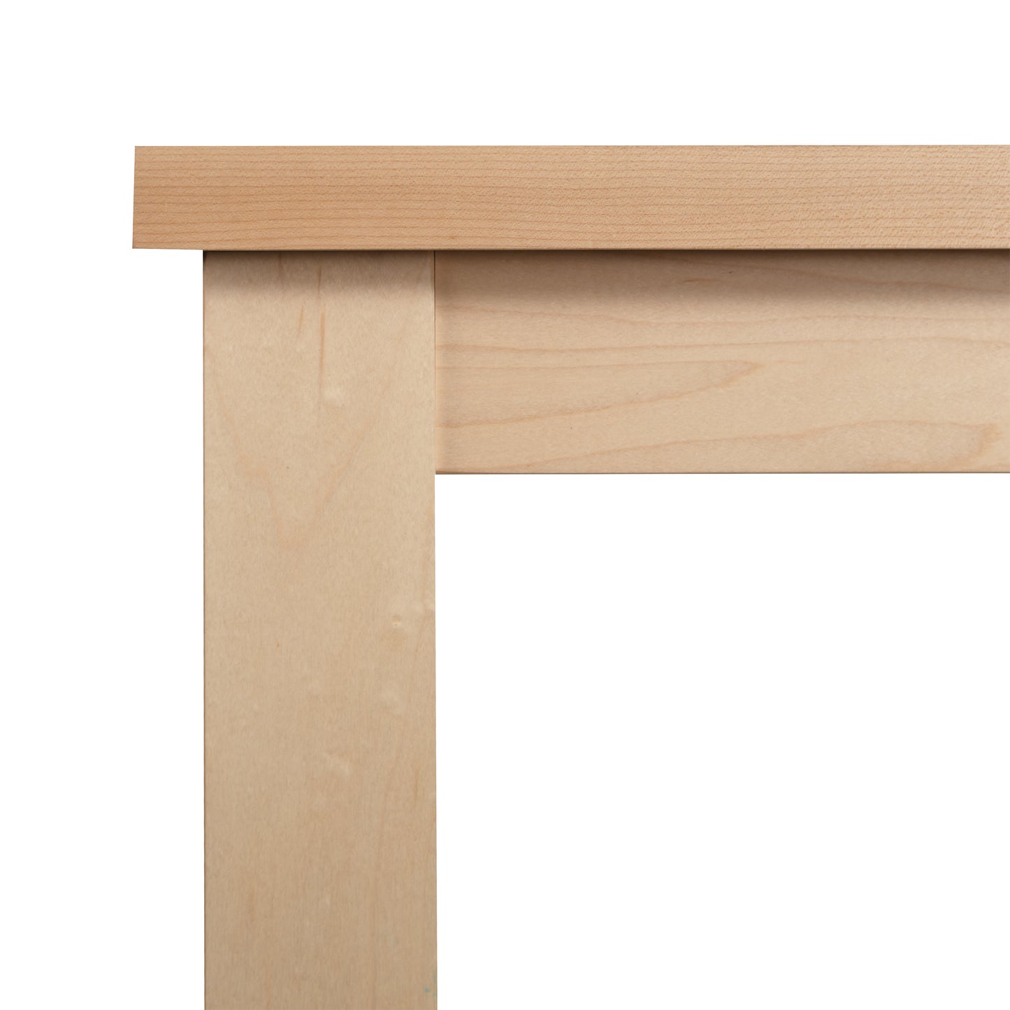 A close-up view of the corner of a Modern Mission Parsons Solid Top Table - Maple - 36"x48" - Clearance by Lyndon Furniture, handcrafted in Vermont. The image showcases the junction between the tabletop and table legs, emphasizing the smooth, natural wood grain and simple, clean lines of this eco-friendly design.