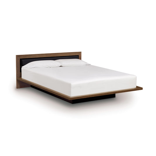 The Moduluxe Platform Bed with Upholstered Headboard - 29" Series by Copeland Furniture features a wooden frame and an upholstered headboard, elegantly complemented by a white mattress.