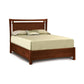 A solid cherry wood Copeland Furniture Monterey Storage Bed with a light beige bedsheet, two pillows, an accent cushion, and underbed storage in a white background setting.