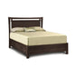 A solid cherry wood queen-sized Copeland Furniture Monterey Bed with a light-colored bedding set and underbed storage in a white background.