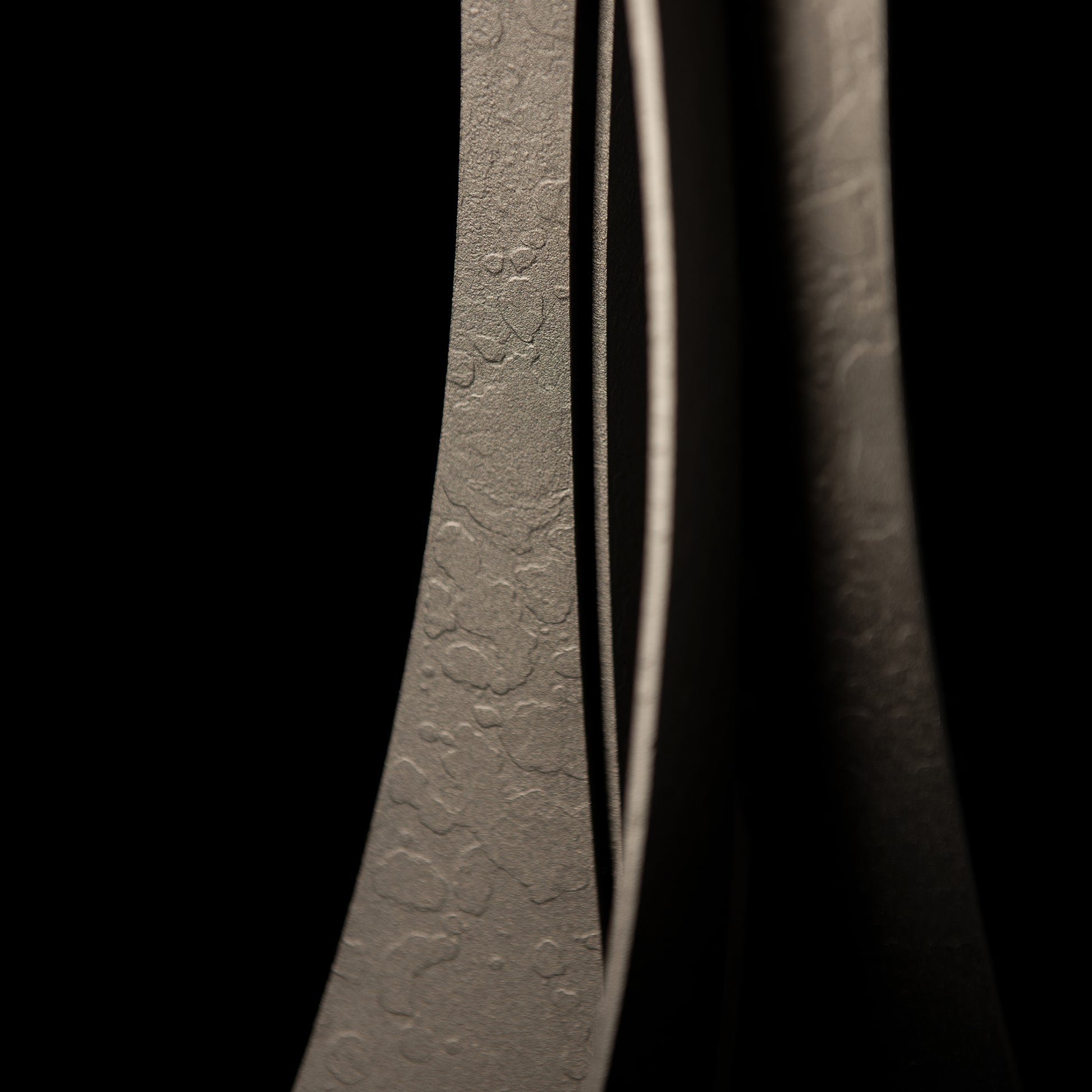 Close-up of a hand-crafted Hubbardton Forge Moreau Table Lamp in low light, creating a play of light and shadow that emphasizes the contours and details.