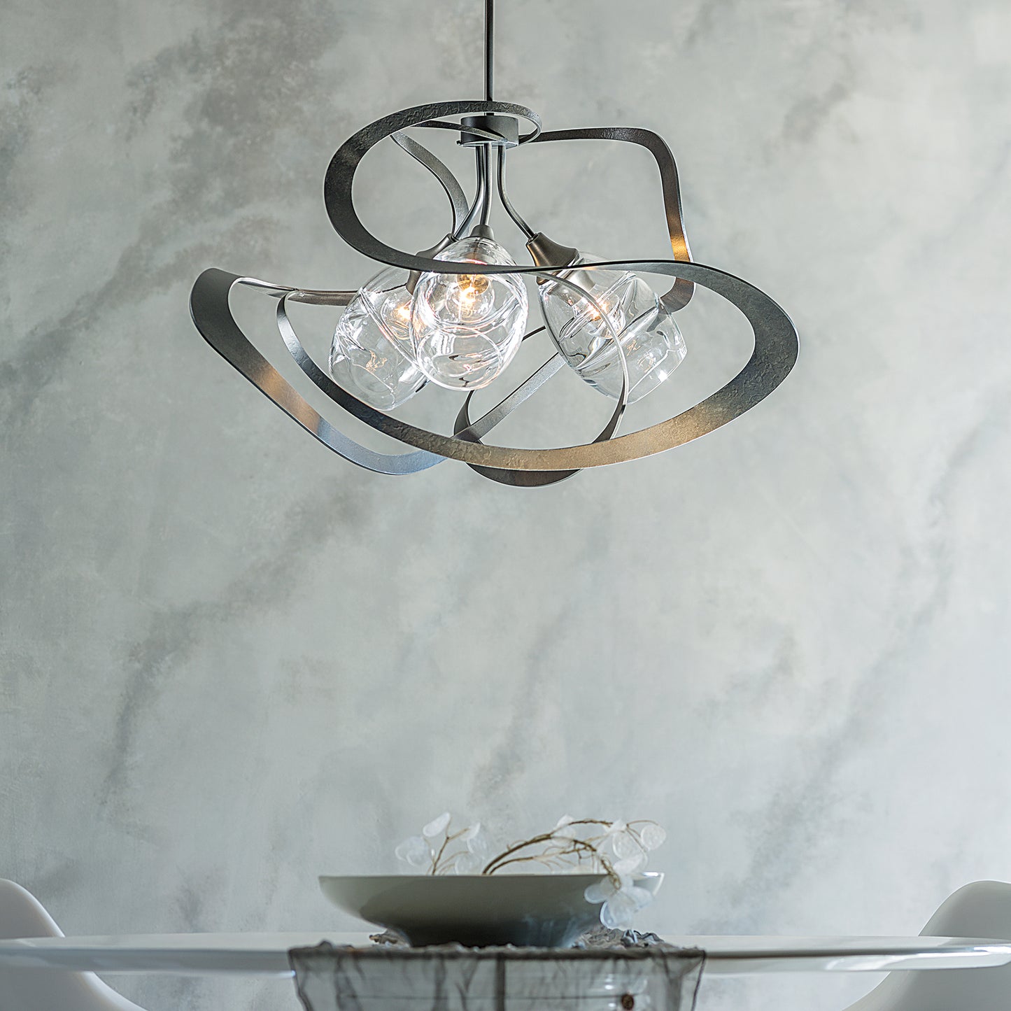 Nest Pendant by Hubbardton Forge: three exposed bulbs, curved metal design, complements a round table.