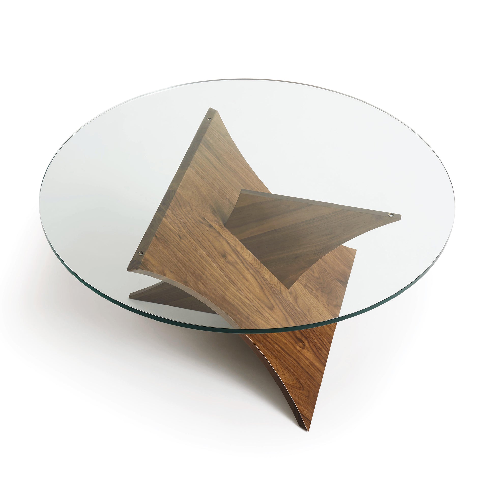 A modern Copeland Furniture Planes Round Glass Top Coffee Table with a tempered glass top resting on a wooden base shaped like a three-dimensional star.
