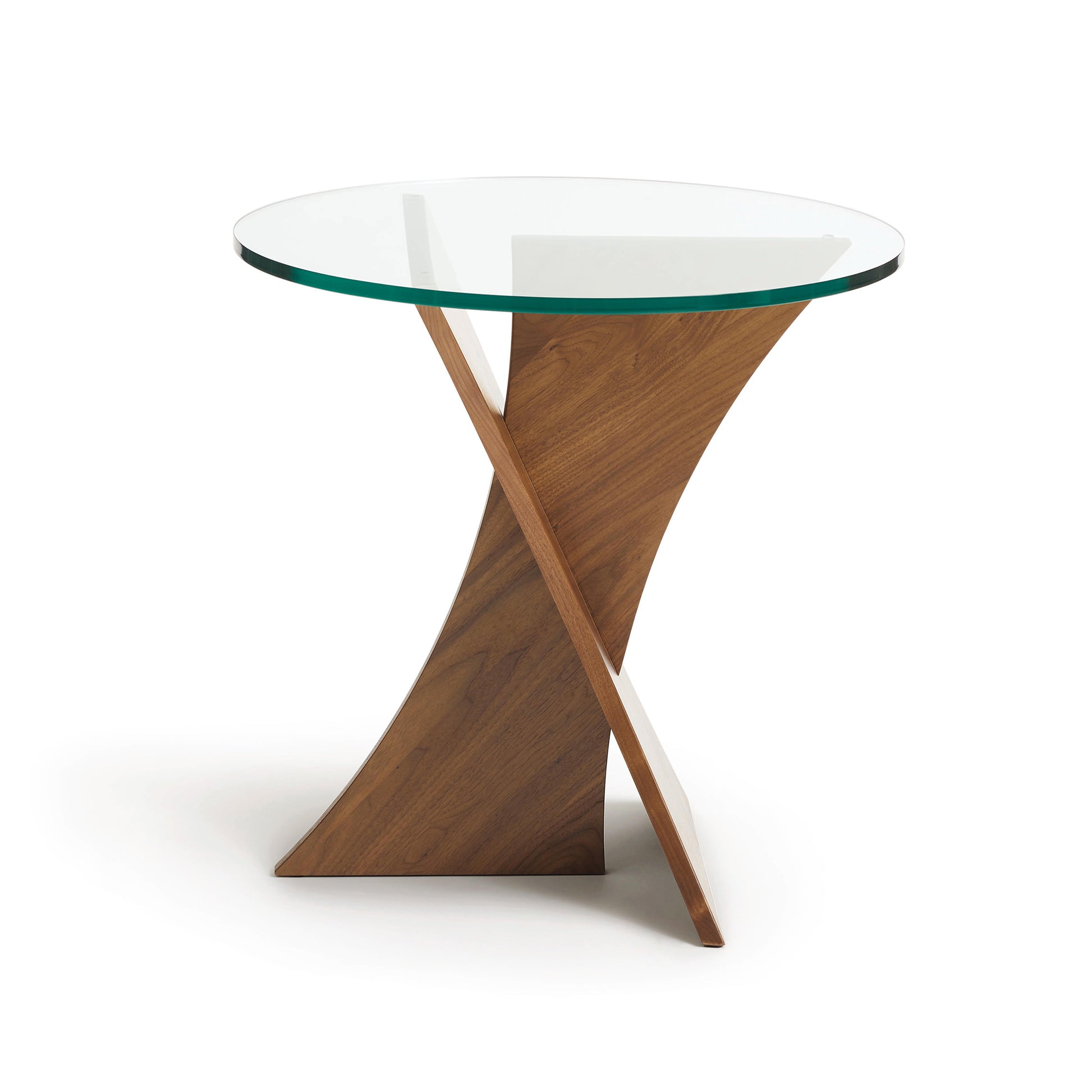 A modern Planes Round Glass Top End Table with a wooden cross base by Copeland Furniture on a white background.